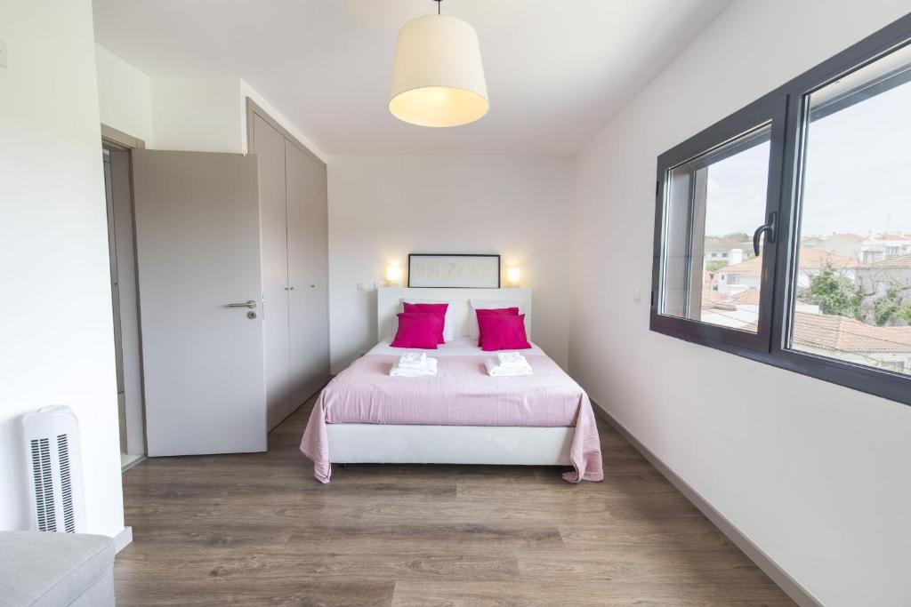 a bedroom with a bed with pink sheets and a window at modern flat in Estoril