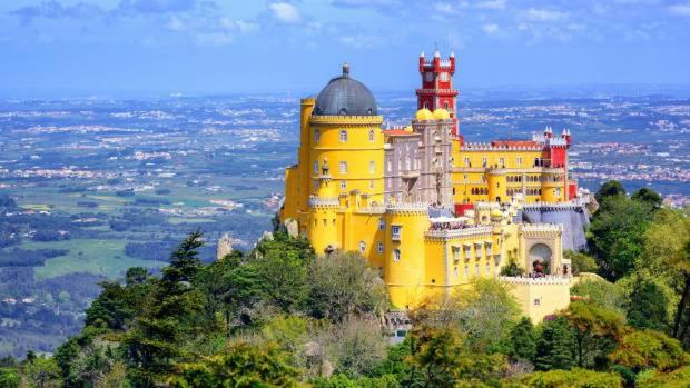 a large yellow building on top of a mountain at modern flat in Estoril
