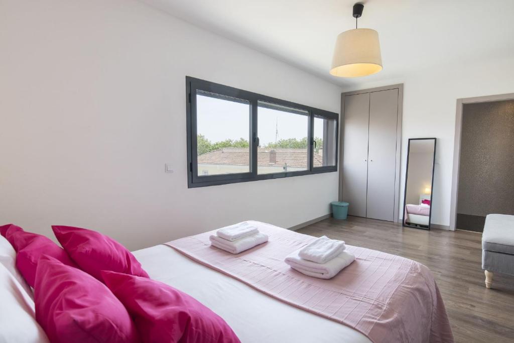a white bedroom with a large bed with pink pillows at modern flat in Estoril