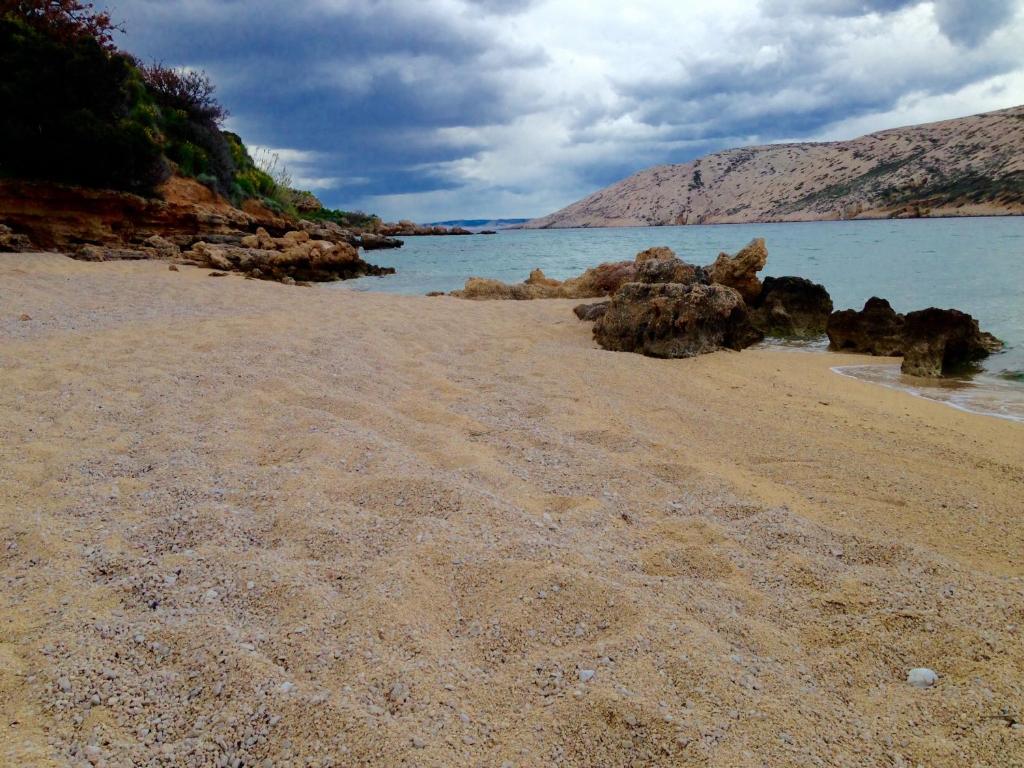 a sandy beach with rocks in the water at Apartments Ljubica in Barbat na Rabu