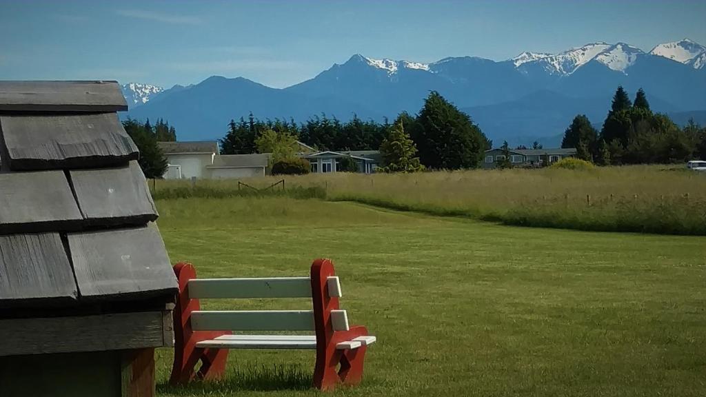 a bench sitting in a field with mountains in the background at Greenhouse Inn by the Bay in Sequim