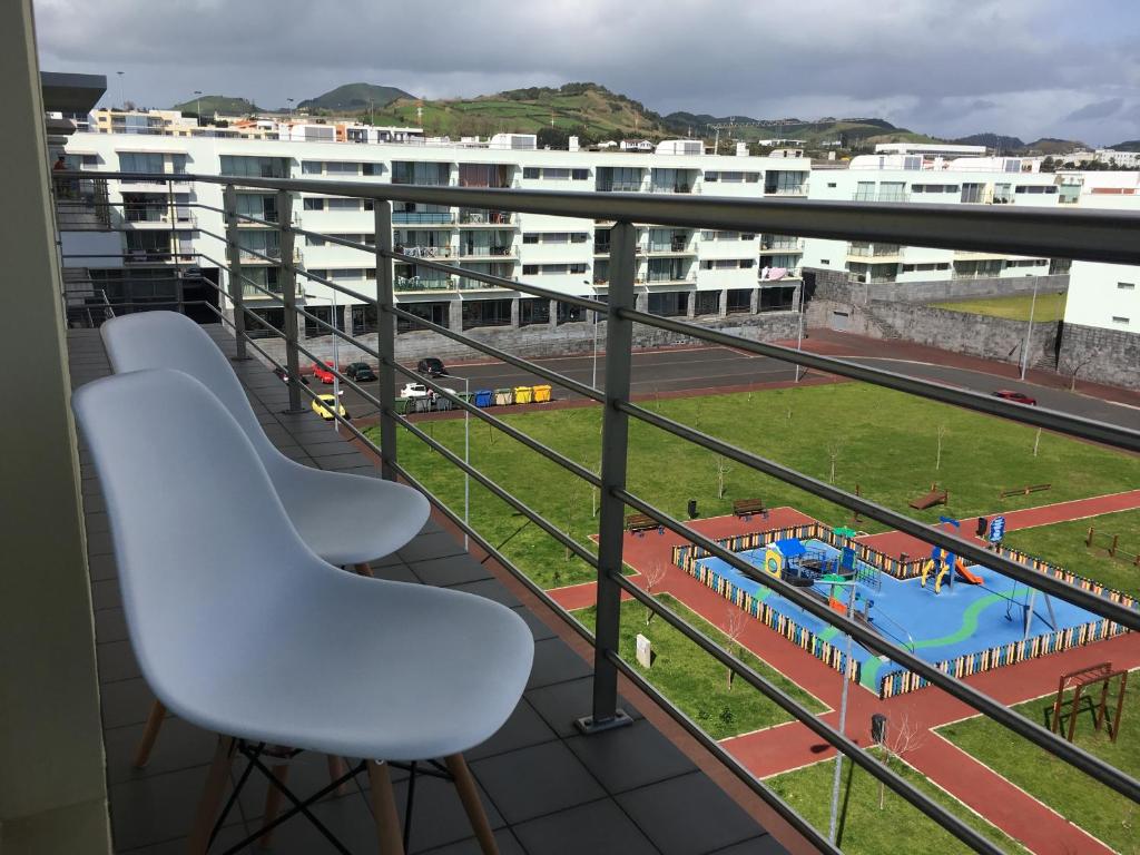 ポンタ・デルガダにあるAzores Paim Apartmentのプールを望むバルコニー(白い椅子2脚付)