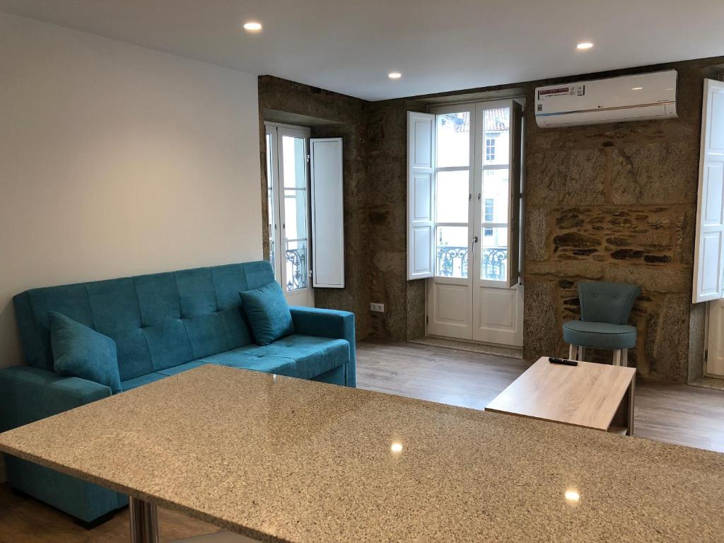 uma sala de estar com um sofá azul e uma mesa em Apartamento luaS em Santiago de Compostela