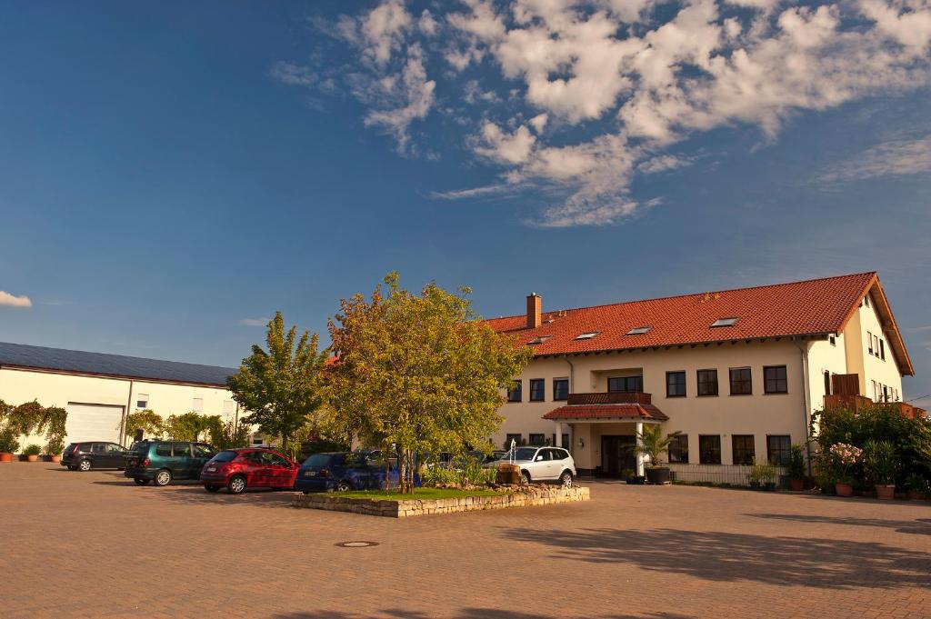 a building with cars parked in a parking lot at Weingut Sandwiese Winzerhotel in Worms