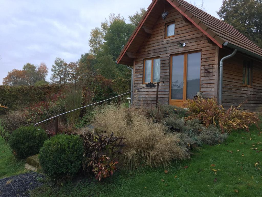 a log cabin with a window and some bushes at au balcon du bonheur in Malandry