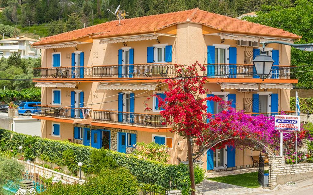 ein großes Gebäude mit blauen Fenstern und einem Baum in der Unterkunft Hotel Arion in Nydri