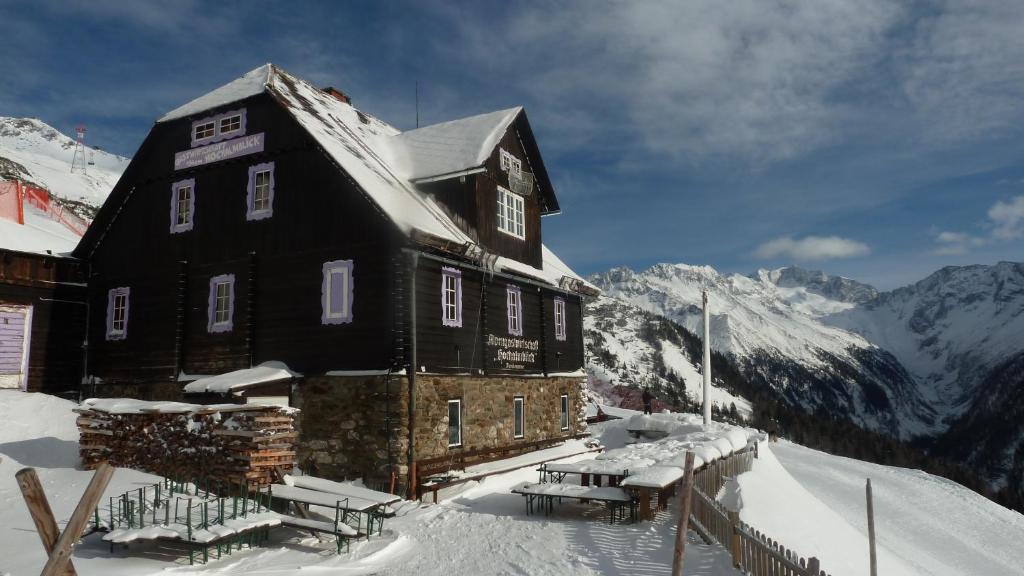 a large wooden building in the snow with mountains at Hochalmblick in Mallnitz