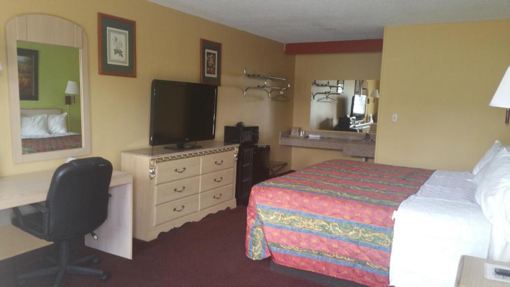 um quarto de hotel com uma cama, uma secretária e uma televisão em ECONOMY INN & SUITES em Harrisburg