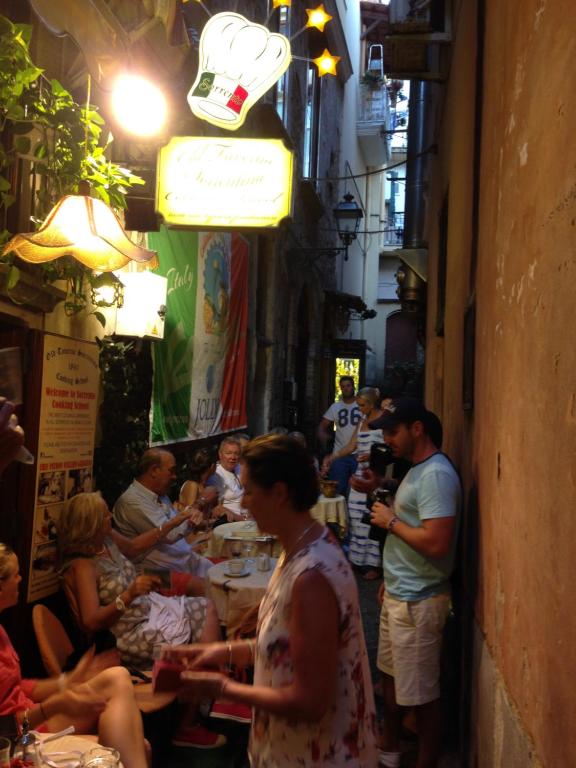 een groep mensen die aan tafels in een straat zitten bij Old Taverna Sorrentina in Sorrento