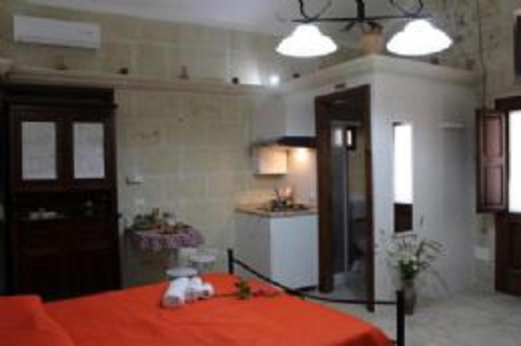 1 Schlafzimmer mit einem Bett mit orangefarbener Bettwäsche und einer Küche in der Unterkunft Antica Dimora del Salento in Martano