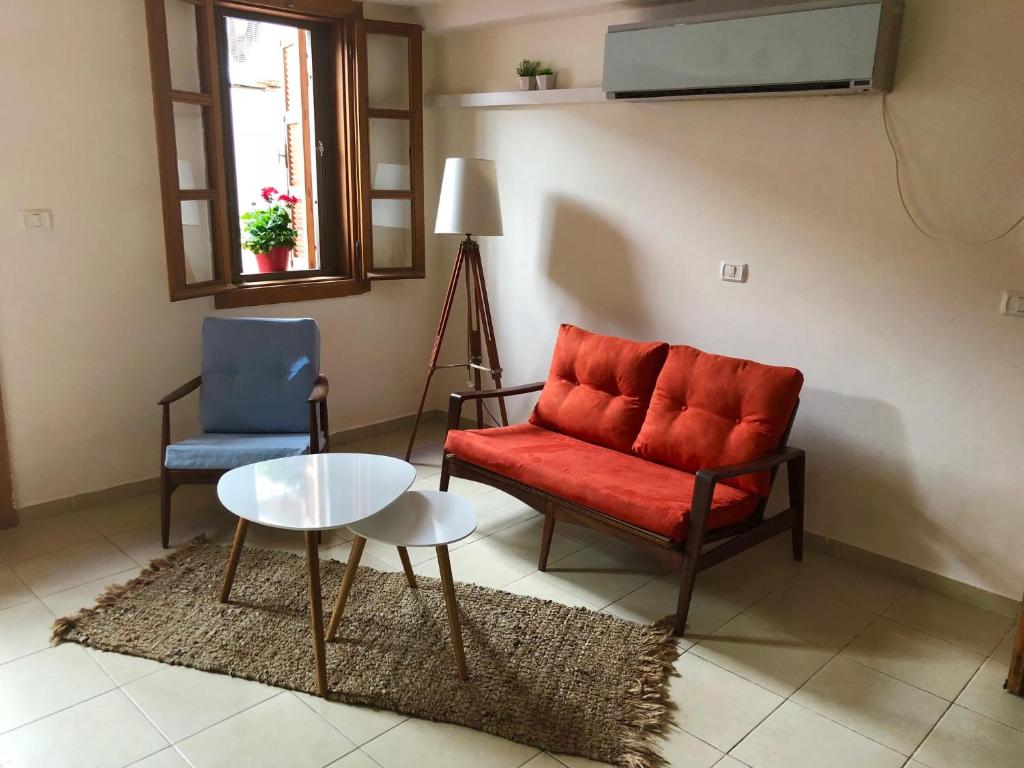 a living room with a red chair and a table at Helen Apartment in Tel Aviv