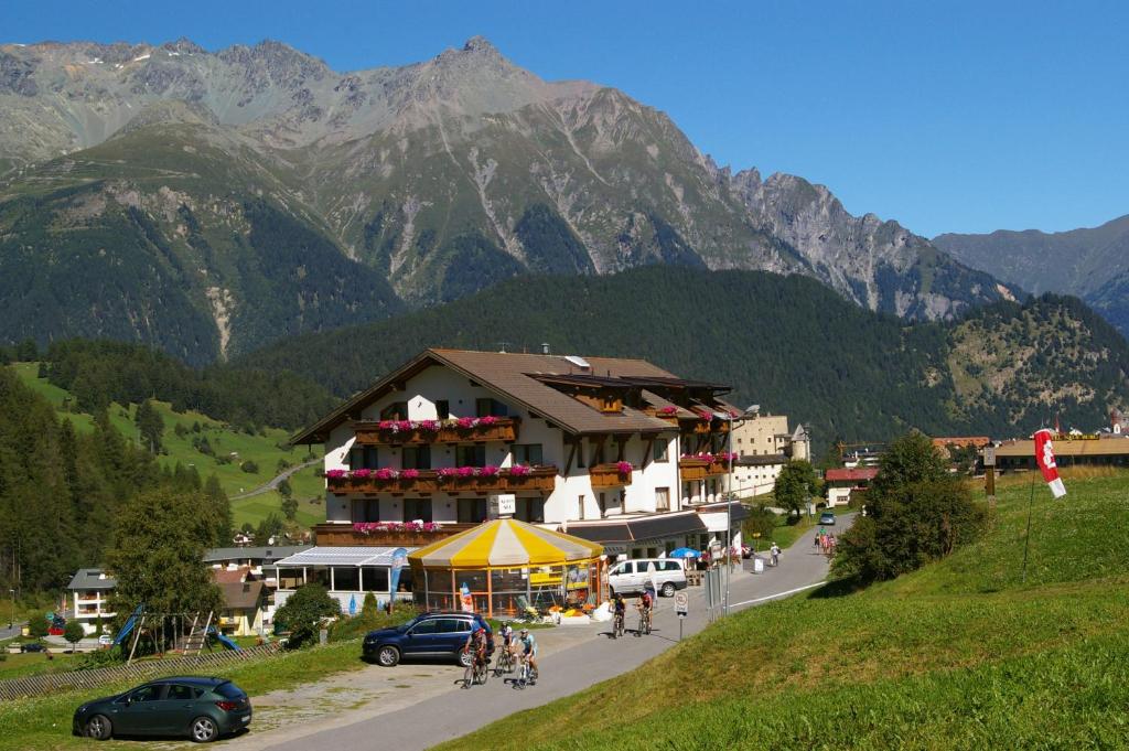 a building on a hill with mountains in the background at Gasthof Martha in Nauders