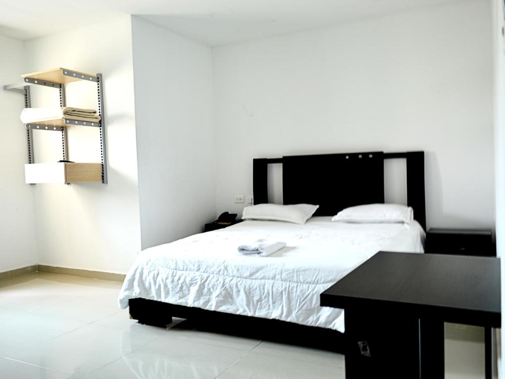 a bedroom with a bed with a black desk and a table at Hotel Intersuites in Barranquilla