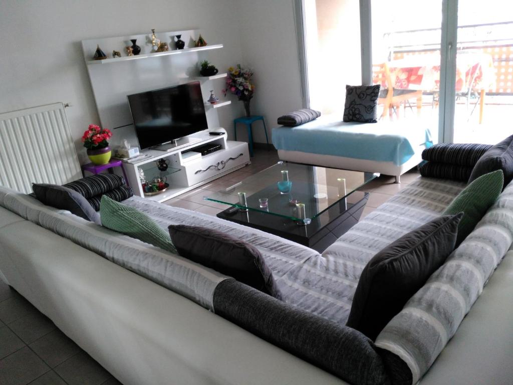 a living room with a large couch and a tv at Appartement F3 avec Parking privée in Saint-Priest