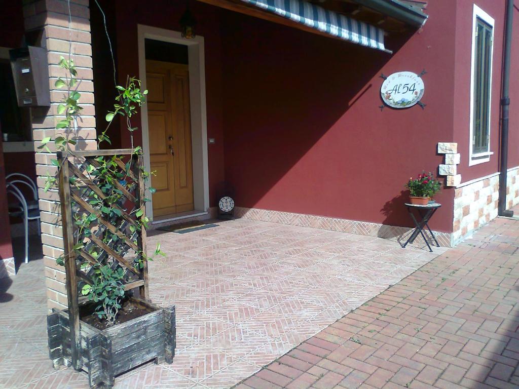 a building with a red wall with a door and plants at Al 54 in San Giorgio Di Mantova