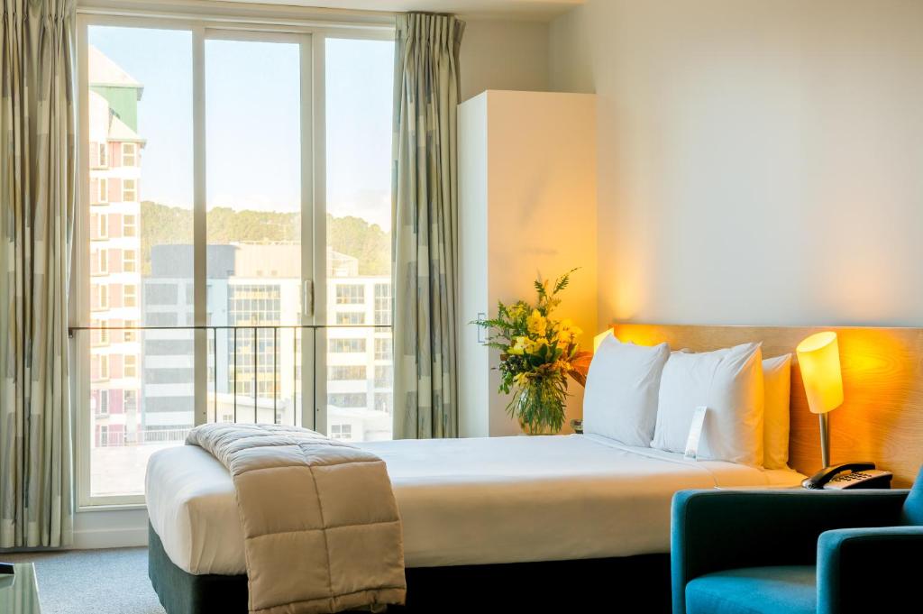 um quarto de hotel com uma cama e uma grande janela em Astelia Apartment Hotel em Wellington