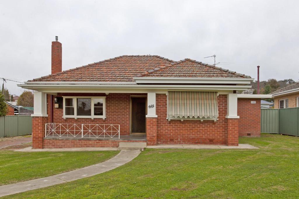 a red brick house with a grass yard at Red Brick Beauty - Central Cottage in Albury