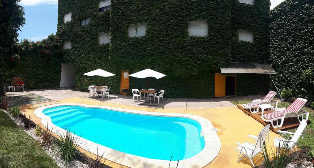 una piscina frente a un edificio con sillas y sombrillas en Hosteria del Sur en Villa Gesell