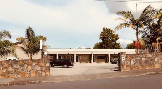 un edificio con un'auto parcheggiata in un parcheggio di Phoenix Palm Motel ad Auckland