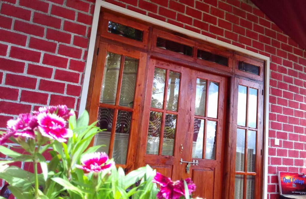 budynek z czerwonej cegły z drewnianymi drzwiami i kwiatami w obiekcie Opal Cottage Ella w mieście Ella
