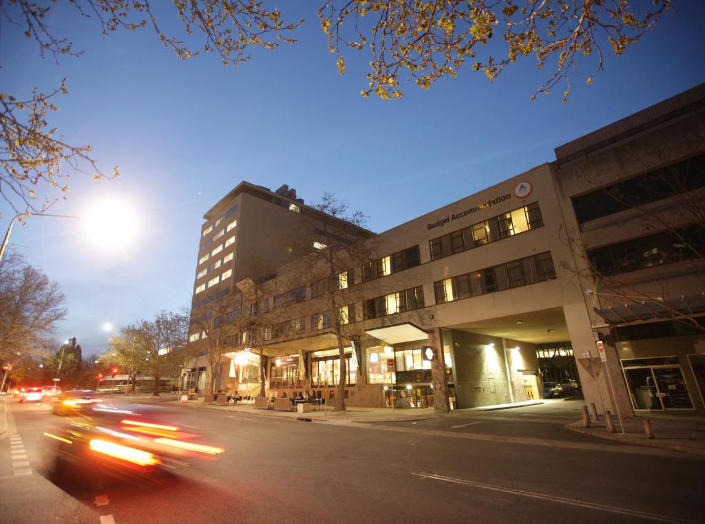 The Village Hostels Canberra في كانبرا: شارع المدينة فيه سيارات تمر فوق مبنى