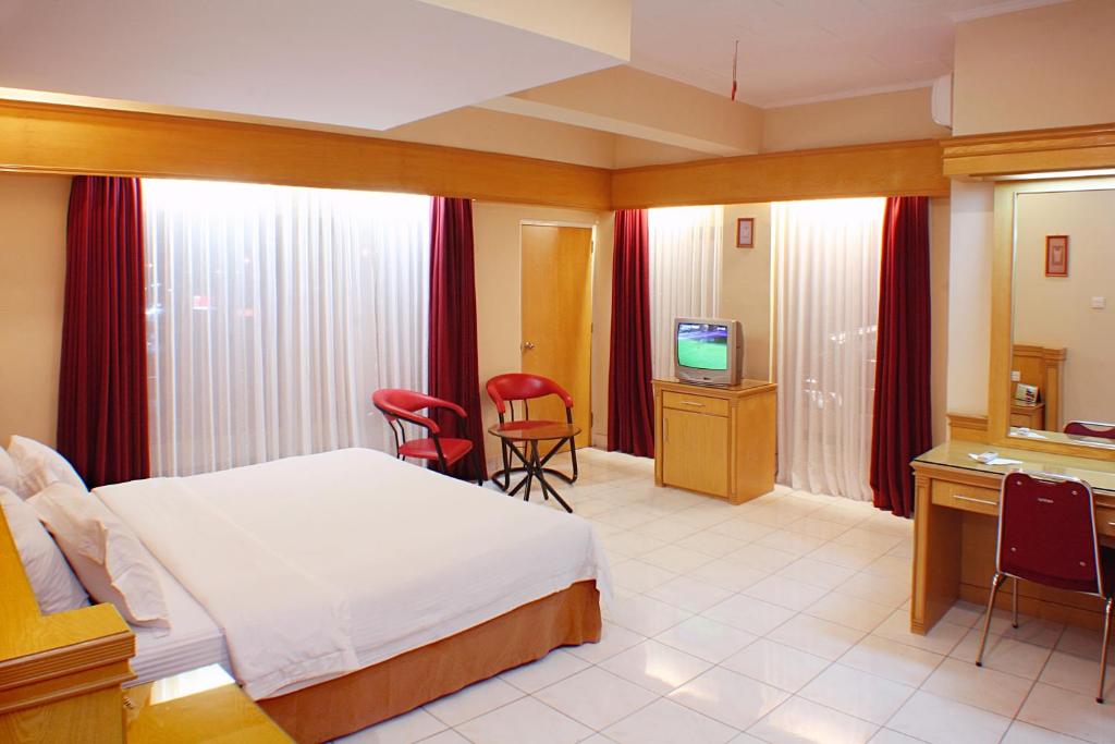 une chambre d'hôtel avec un lit et une télévision dans l'établissement Hotel Hangtuah, à Padang
