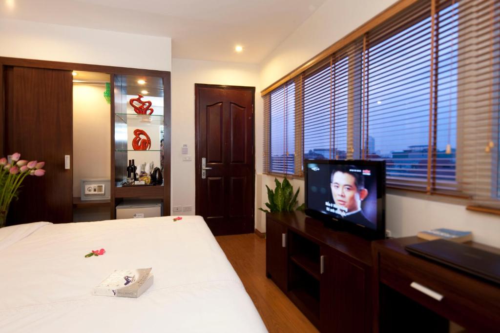 a bedroom with a bed and a tv on a dresser at Rising Dragon Legend Hotel in Hanoi