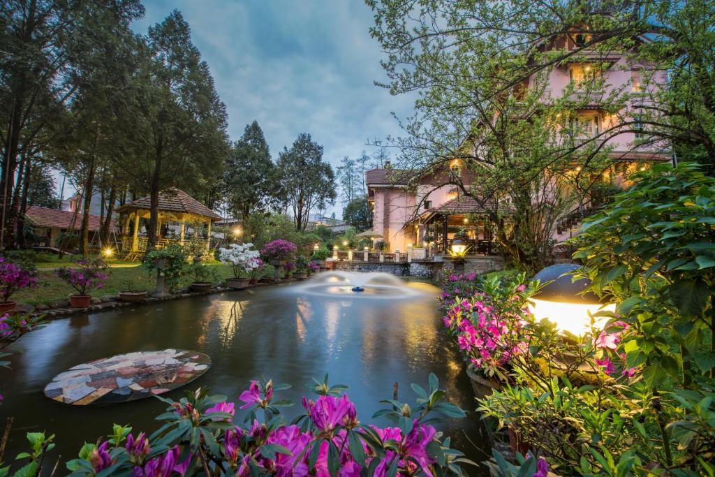 a pond in front of a building with flowers at Sapa Garden Bed and Breakfast in Sa Pa