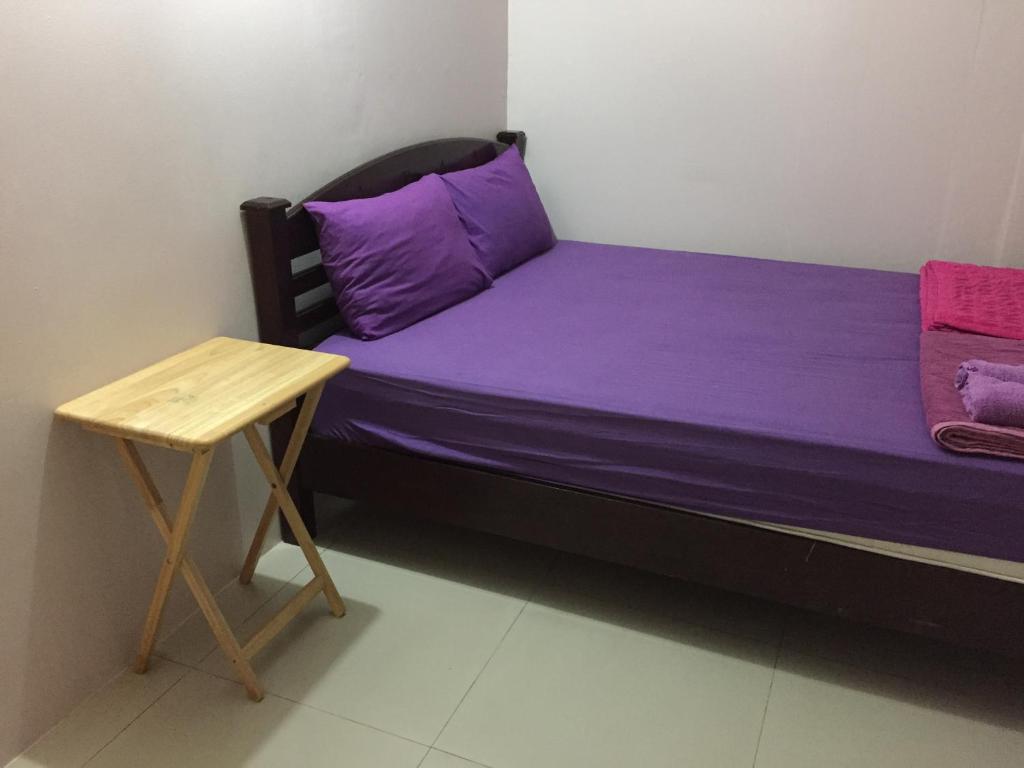 Cama pequeña con sábanas púrpuras y mesa en Honey Place Guesthouse,special rate for long stay, en Bangkok