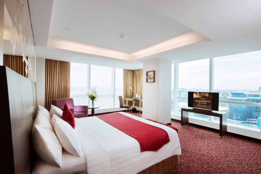 a hotel room with a bed and a large window at The Alana Surabaya in Surabaya