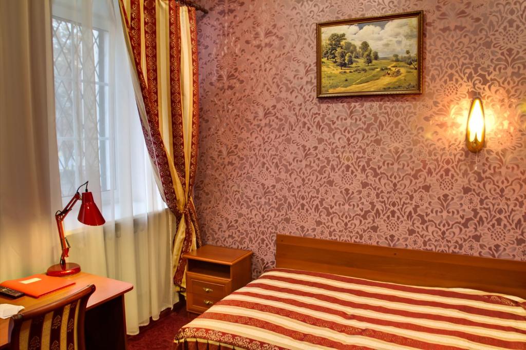 a bedroom with a bed and a desk and a window at Suvorovskaya Hotel in Moscow