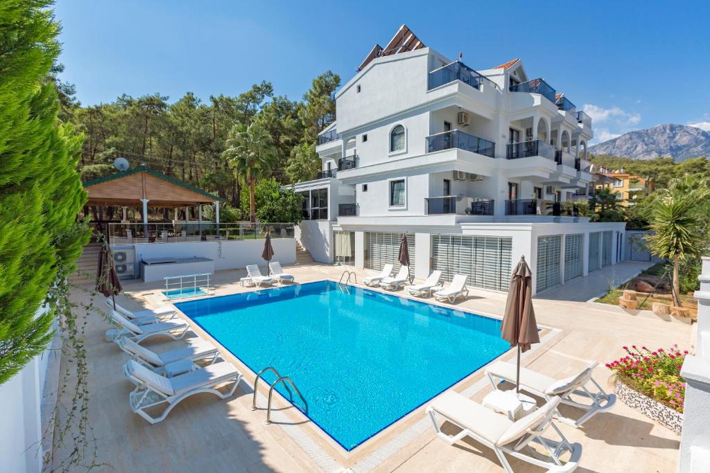 a large white house with a swimming pool and chairs at Forest Park Hotel in Kemer