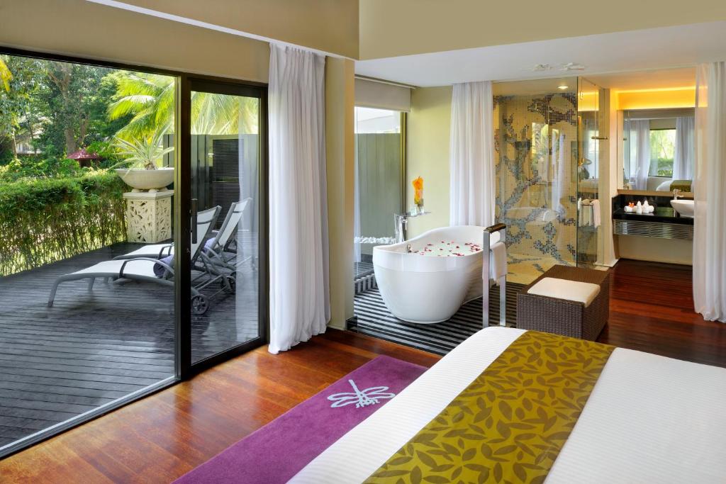 una camera da letto con vasca e un balcone con bagno di Thistle Port Dickson Resort a Port Dickson