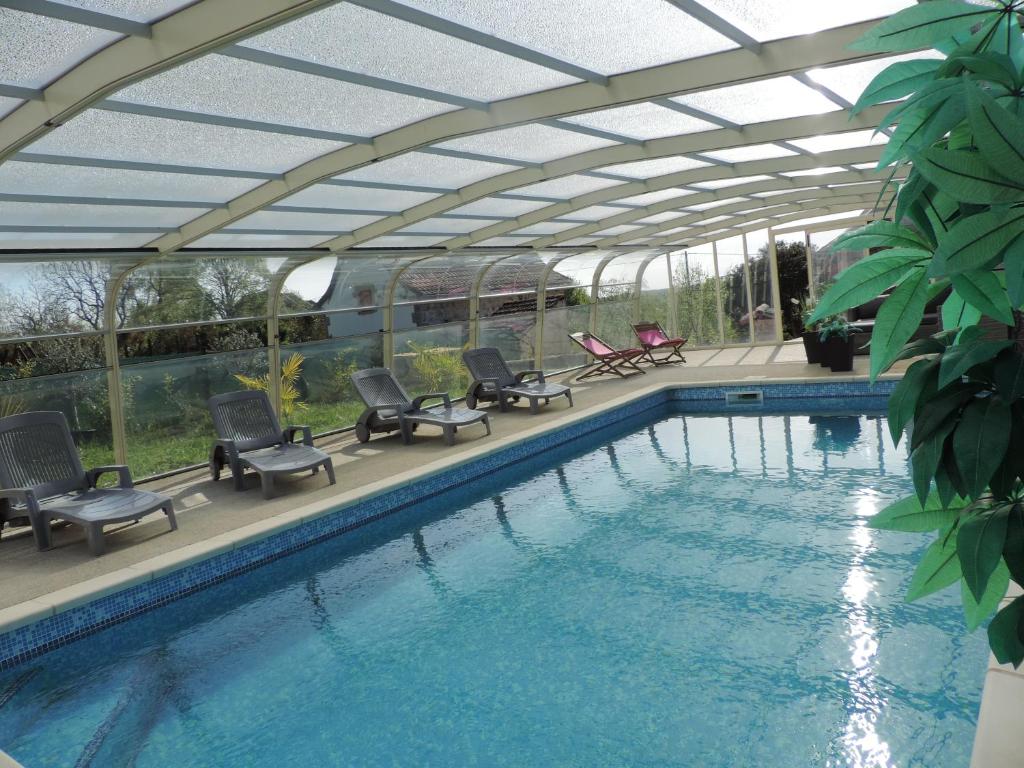 a swimming pool with chairs and a roof over it at Le Mas de Cascabel in Causse et Diege