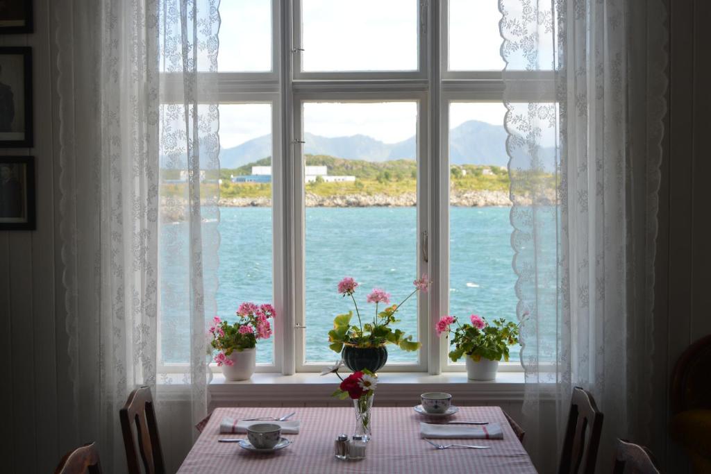 a table with flowers sitting in front of a window at Skagakaia in Bø i Vesterålen