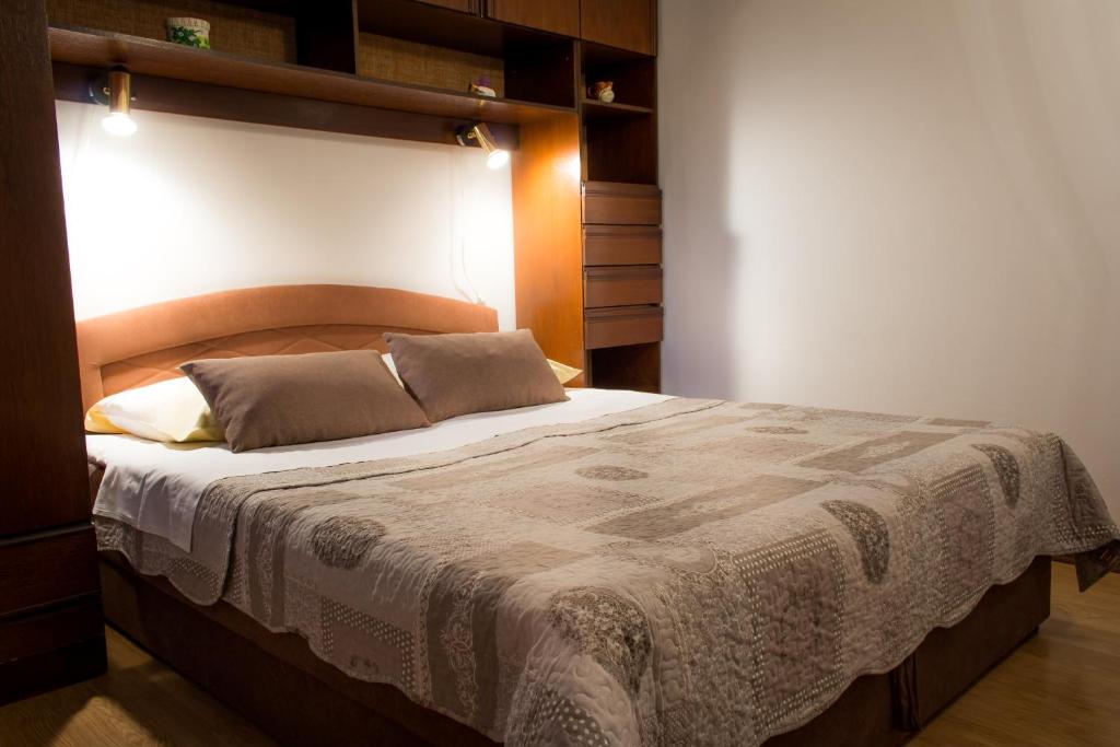 a bedroom with a large bed with a wooden headboard at Apartman Đina in Risika