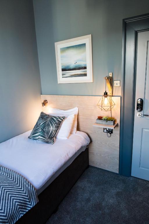 a bedroom with a bed with a pillow and a lamp at The Fullerton Arms in Ballintoy