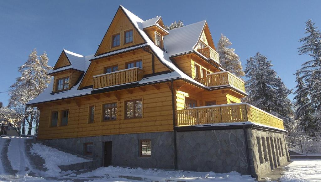 une grande maison en bois avec de la neige au-dessus dans l'établissement Willa Baśka, à Zakopane