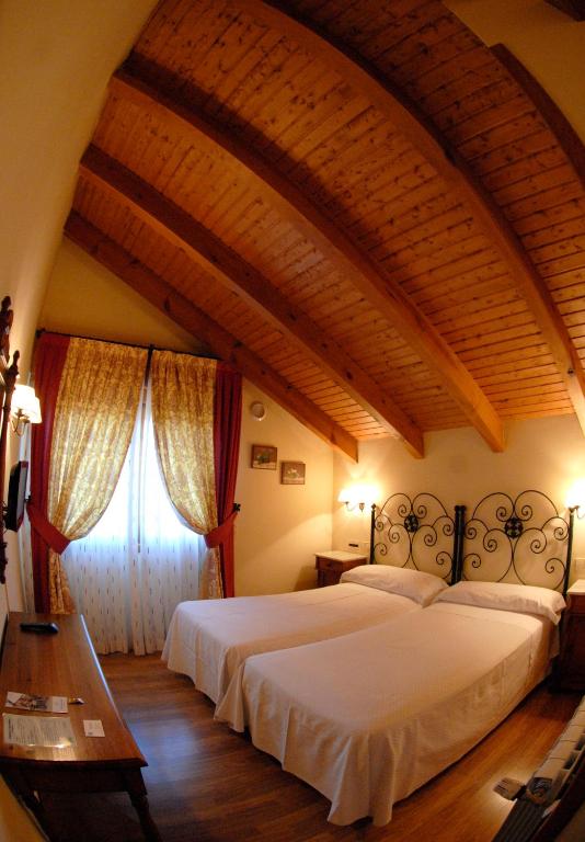 Un dormitorio con dos camas y suelo de madera. en Nava Real, en Navacerrada