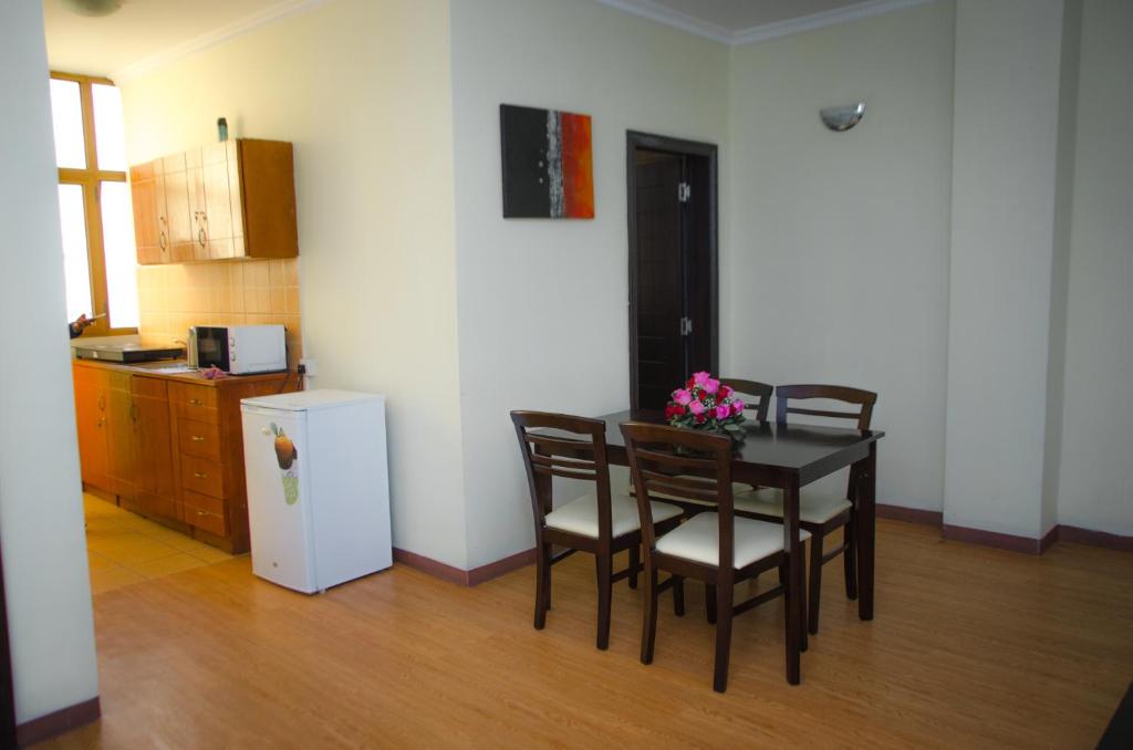 uma cozinha com uma mesa com cadeiras e um frigorífico em Union Hotel Apartments em Addis Ababa