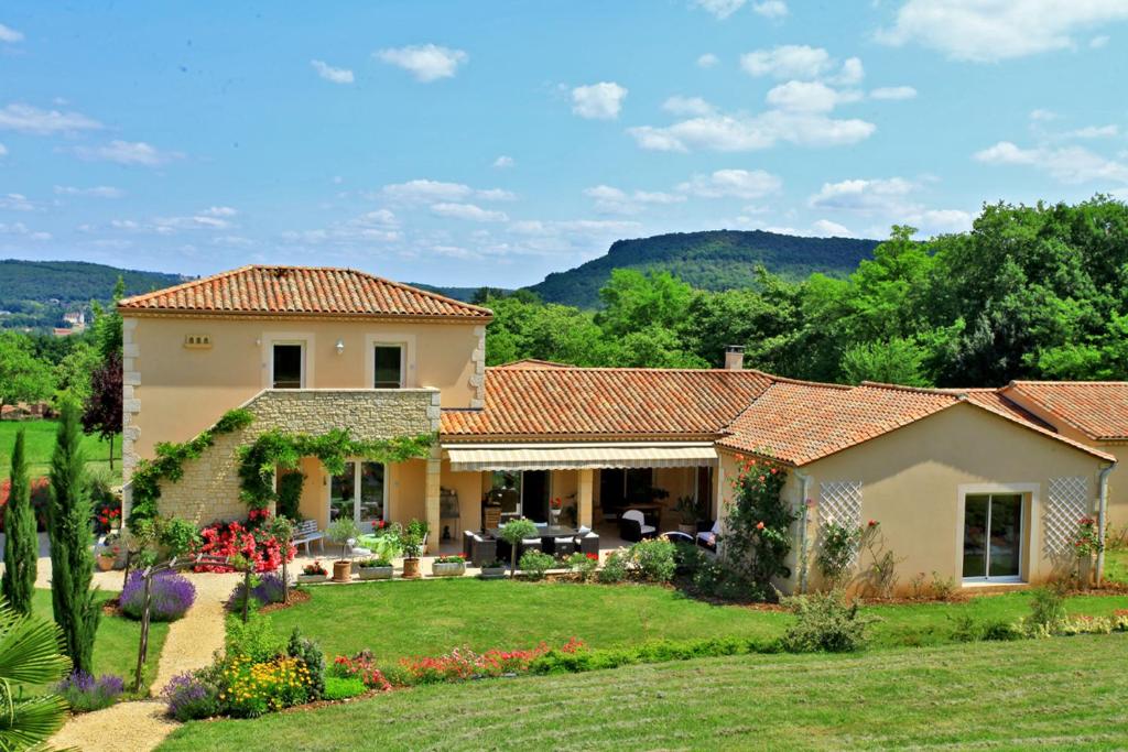 una casa con giardino e montagne sullo sfondo di Les Chenes Rouges a Veyrines-de-Domme