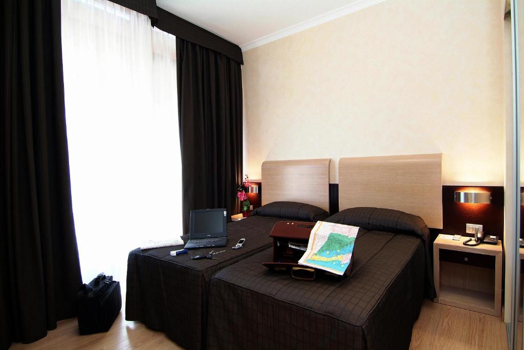 EH Rome Airport Euro House Hotels في فيوميتشينو: غرفة نوم مع سرير مع لاب توب عليه