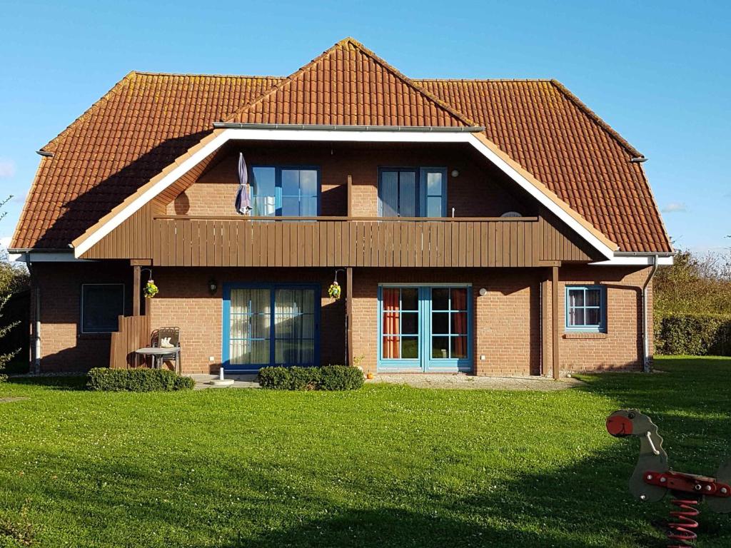 a house with a red roof and a green yard at PEKW6A103-FeWo-Kievitt in Petersdorf auf Fehmarn