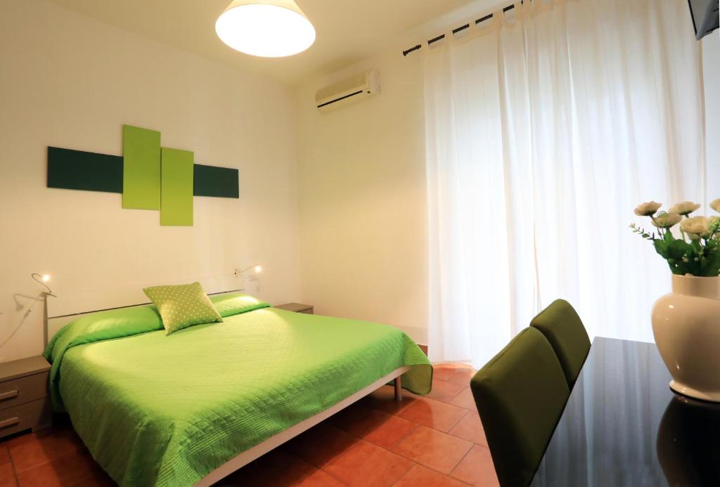 Un dormitorio con una cama verde y un jarrón de flores en Primo Piano Guesthouse - Bari Policlinico en Bari