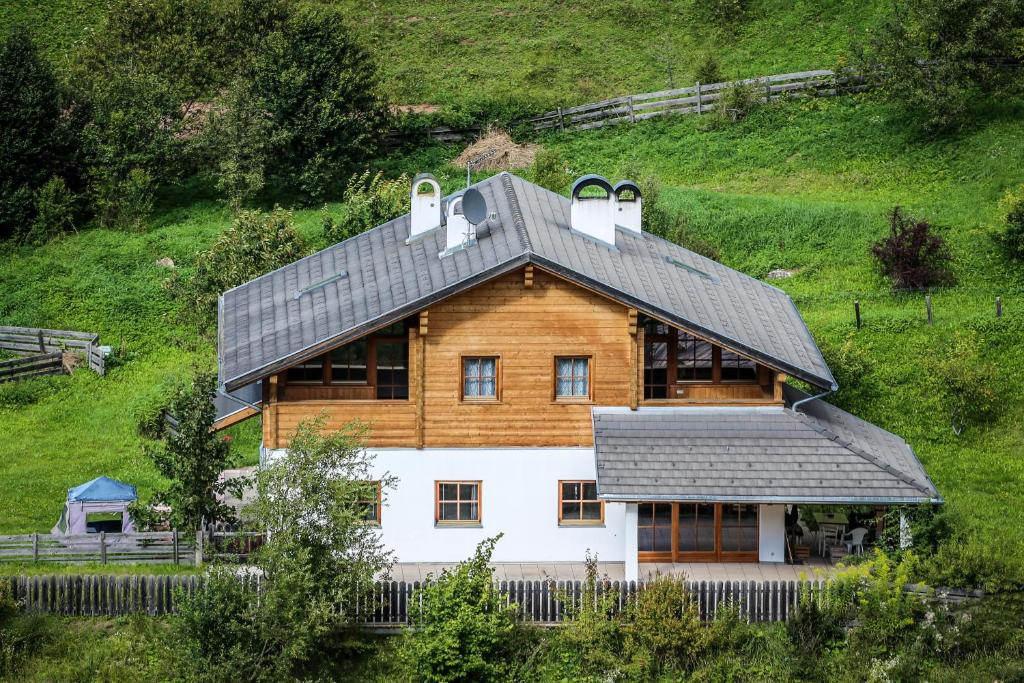 a wooden house with a roof on a hill at Haus Traudi in Nova Ponente