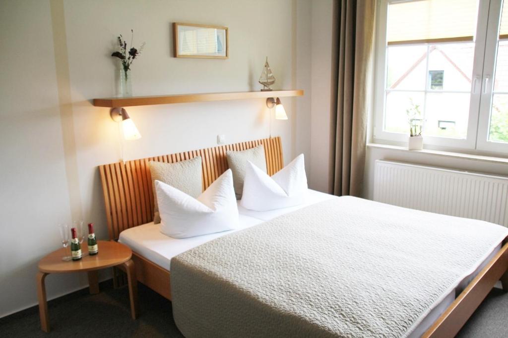 een slaapkamer met een bed met witte lakens en een raam bij Pension "Zur Steilküste" in Boltenhagen