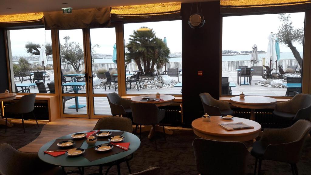 a restaurant with tables and chairs and a large window at Hôtel Les Brises in La Rochelle