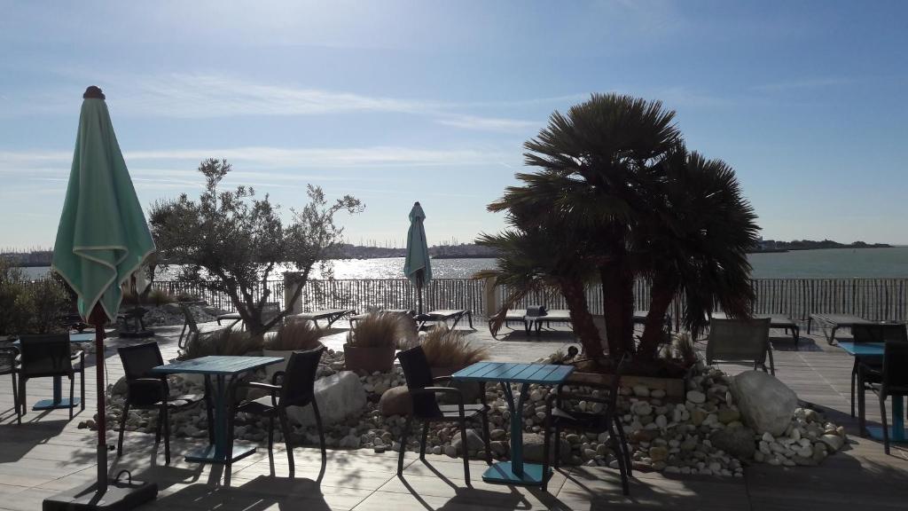 a group of tables and chairs with umbrellas at Hôtel Les Brises in La Rochelle
