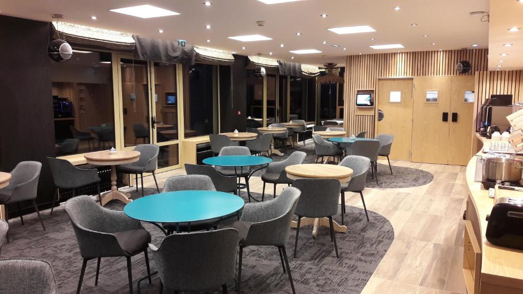a bar with tables and chairs in a restaurant at Hôtel Les Brises in La Rochelle