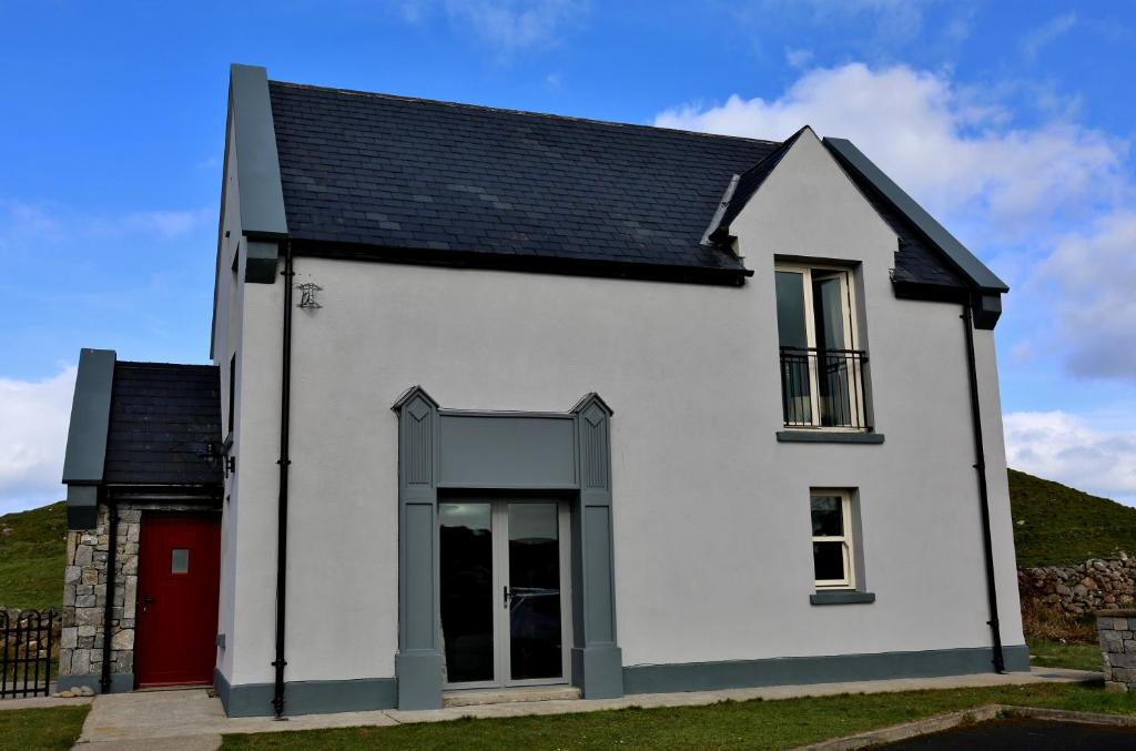 a white house with a black roof and a red door at 11 Doolin Court in Doolin